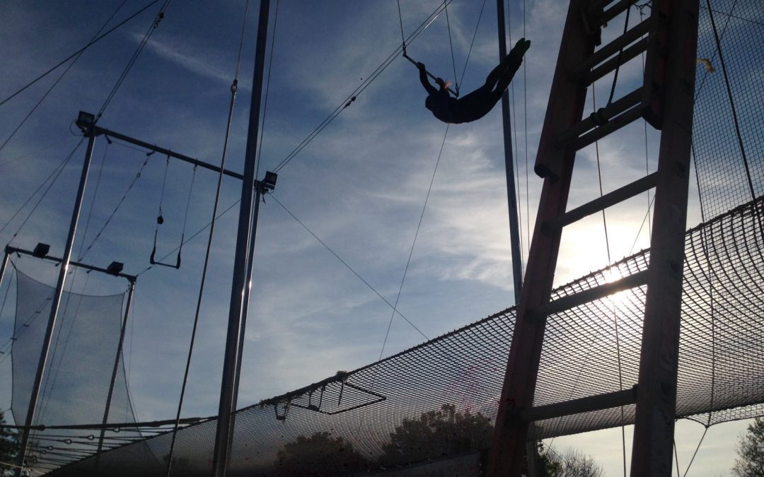 A person using an outdoor trapeze swing under a cloudy sky